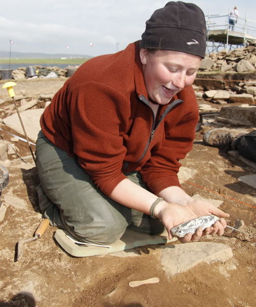 Jo one of our American students lifts an exceptional polished stone axe at the Ness of Brodgar, Orkney