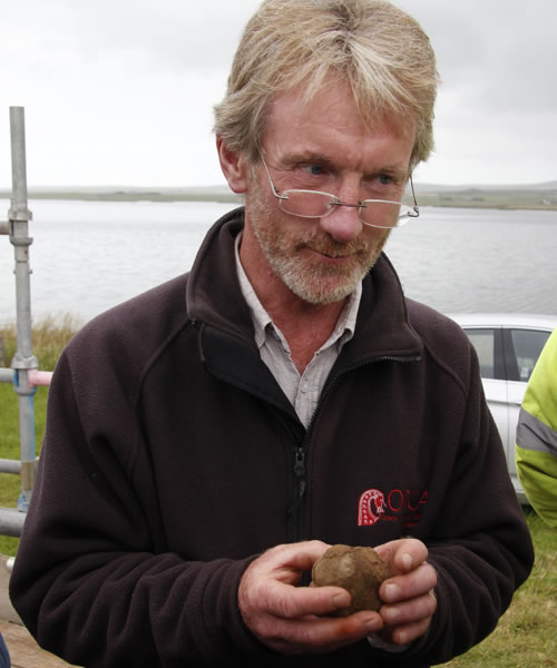 Nick cradles the carved stone ball at the Ness of Brodgar, Orkney