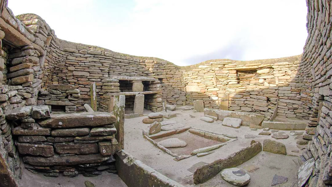 Skara Brae house with fireplace, dresser and beds