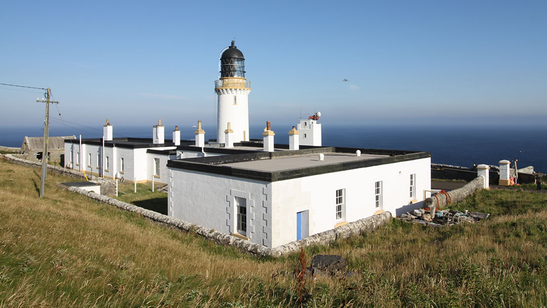 Dunnet Head lighthouse in Caithness with an aeroplane and MV Hamnavoe in the distance