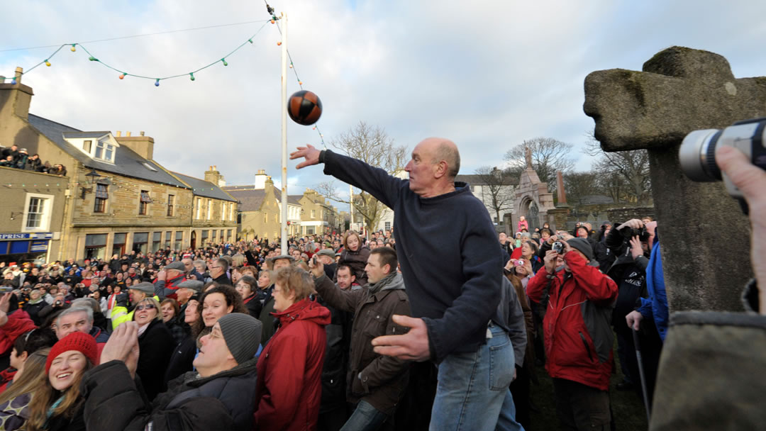 A Ba stalwart throws the Ba' up from Kirk green into Broad Street, Kirkwall