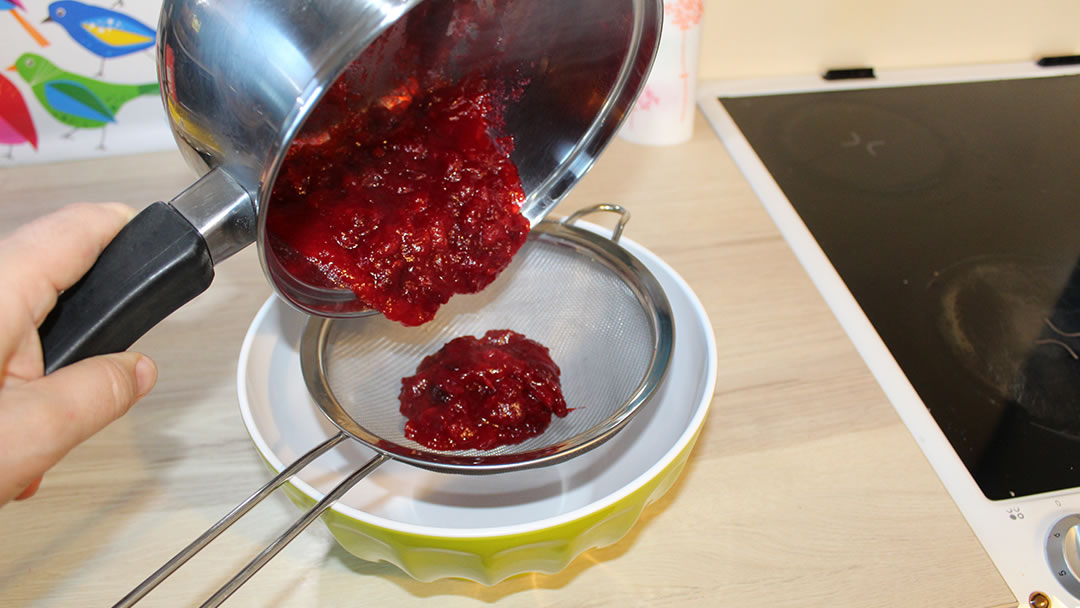 Rubbing the cranberry sauce mixture through a sieve