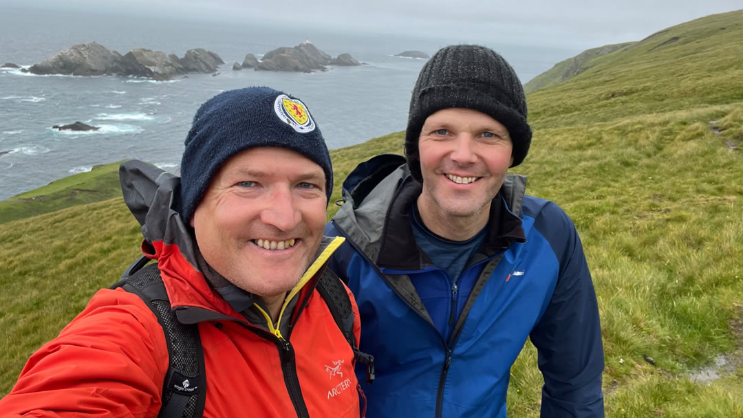 Robin hiking with his neighbour at Hermaness in Shetland with Muckle Flugga in the background