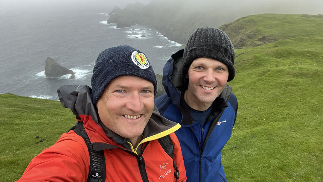 Robin hiking with his neighbour at Hermaness in Shetland with Muckle Flugga in the background