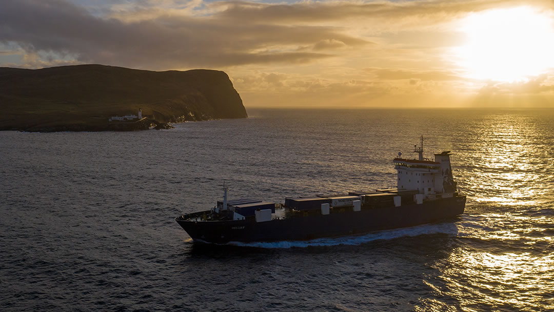 Helliar passes Kirkabister as the freight ship arrives in Shetland Ness