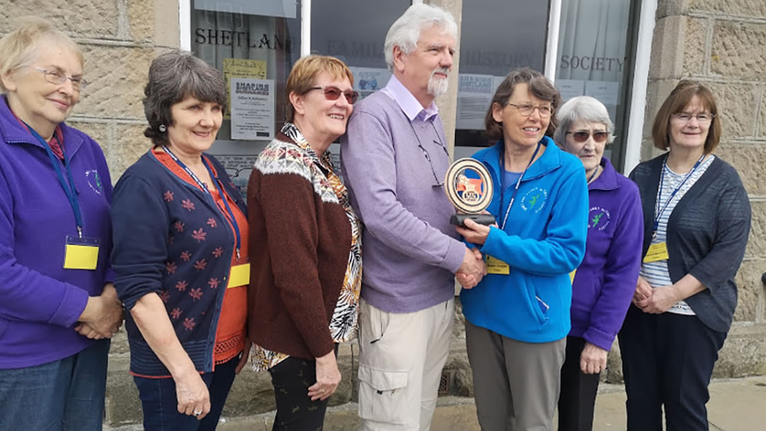 Shetland Family History Society member, Ian Elliott, presenting the society with a plaque he made to those who served in the Merchant Navy WW1and in particular the Harrison Brothers, his great uncles