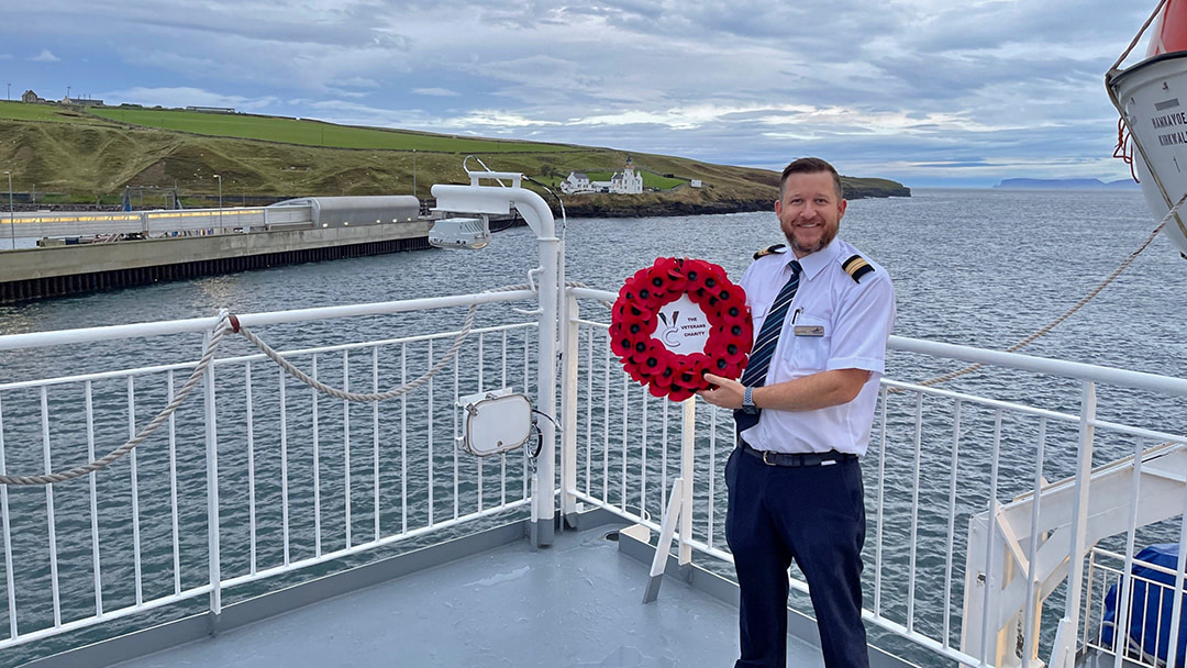 Greg Mouat, Purser on the MV Hamnavoe, holding the Routes of Remembrance Wreath