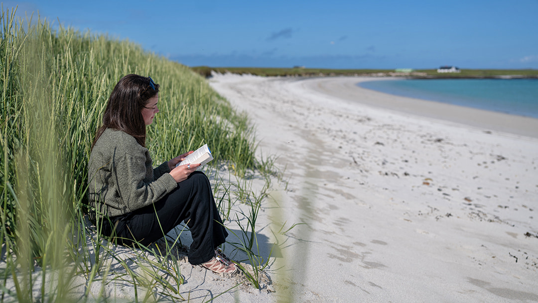 Reading a book on a beach in Orkney